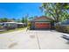 Home exterior with a green paint scheme, red garage door, boat cover, mature trees, and a driveway at 28330 Peterson Camp Rd, Brooksville, FL 34601