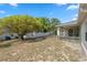 Spacious backyard with partial fencing and mature trees. Includes back of house and covered patio at 3017 Aldoro Ave, Spring Hill, FL 34609