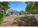 Spacious backyard with mature trees and a glimpse of the rear of the house with a covered patio at 3017 Aldoro Ave, Spring Hill, FL 34609