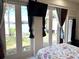 Bright main bedroom with a floral patterned bedspread, marble floors and French doors to the outside at 3037 Leroy W St, Tampa, FL 33607