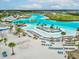 Aerial view of the resort-style community pool, sandy beach, volleyball court, and turquoise water at 30839 Penny Surf Loop, Wesley Chapel, FL 33545