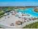 Aerial view of community resort-style lagoon with water slides, white sand beaches, and palm trees perfect for vacation lifestyle at 30839 Penny Surf Loop, Wesley Chapel, FL 33545
