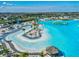Aerial view of community resort-style lagoon with lounge chairs and umbrellas on a white sand beach with an island at 30839 Penny Surf Loop, Wesley Chapel, FL 33545