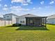 View of the home's back exterior with a screened lanai and well-maintained lawn, perfect for outdoor activities at 30839 Penny Surf Loop, Wesley Chapel, FL 33545