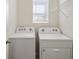 Laundry room with modern side-by-side white washer and dryer and shelving at 30839 Penny Surf Loop, Wesley Chapel, FL 33545