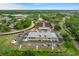 Aerial view of a community clubhouse, parking, lake, and tennis courts in a wooded area at 3160 Whispering Pines Ct, Spring Hill, FL 34606