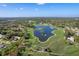 Scenic aerial view highlights the sprawling golf course, a beautiful lake, and mature landscaping at 3160 Whispering Pines Ct, Spring Hill, FL 34606