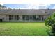 Spacious backyard featuring a lush green lawn and multiple sliding glass doors for easy indoor-outdoor living at 3160 Whispering Pines Ct, Spring Hill, FL 34606