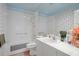 Bright bathroom with tub-shower, white cabinets, and floral accent wall at 3160 Whispering Pines Ct, Spring Hill, FL 34606