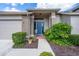 Welcoming front entrance with a blue door, brick accents, and lush, green landscaping at 3160 Whispering Pines Ct, Spring Hill, FL 34606