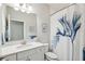 Clean bathroom with white cabinetry, framed mirror, floral shower curtain, and sink at 4012 Dragonfly Trl, Odessa, FL 33556