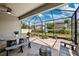 Enclosed patio area with a dining table and chair set on a stone patio with an umbrella and seating at 4012 Dragonfly Trl, Odessa, FL 33556