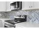 Close-up of stainless steel stove with white countertops and unique backsplash at 4503 Jacona Dr, Hernando Beach, FL 34607