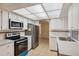 Well-lit kitchen with white cabinets, stainless steel appliances, and a view into the dining area at 4559 Crescent Rd, Spring Hill, FL 34606