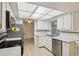 Bright kitchen features white cabinets, stainless steel appliances, tile flooring, and a skylight at 4559 Crescent Rd, Spring Hill, FL 34606