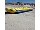 Long yellow inflatable banana boat on beach near many people sitting under umbrellas at 5335 Embassy Ave # 5335, New Port Richey, FL 34652