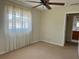 This bedroom features neutral paint and carpet, along with a large window and adjoining bathroom at 5335 Embassy Ave # 5335, New Port Richey, FL 34652