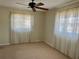This bedroom features neutral paint and carpet, along with a ceiling fan and dual windows with decorative curtains at 5335 Embassy Ave # 5335, New Port Richey, FL 34652