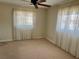 A cozy bedroom with ceiling fan, neutral paint and carpet, and dual windows with decorative curtains at 5335 Embassy Ave # 5335, New Port Richey, FL 34652