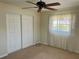 This bedroom features a ceiling fan, closet with sliding doors, and large window with neutral carpet at 5335 Embassy Ave # 5335, New Port Richey, FL 34652
