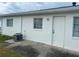 Back of a white single-story building showing a grassy backyard with a small patio area and AC unit at 5335 Embassy Ave # 5335, New Port Richey, FL 34652