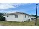 Rear view of a white single-story building showing a grassy backyard with a small patio area at 5335 Embassy Ave # 5335, New Port Richey, FL 34652