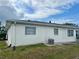 Back of a white single-story building showing a grassy backyard with a small patio area and AC unit at 5335 Embassy Ave # 5335, New Port Richey, FL 34652