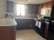 Kitchen featuring dark wood cabinetry and black appliances set atop neutral tile flooring at 5335 Embassy Ave # 5335, New Port Richey, FL 34652