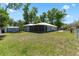 Wide view of the backyard showing the entire house, screened porch, a storage shed, and fenced perimeter at 5342 Leisure St, Dade City, FL 33523