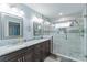Modern bathroom featuring granite countertops, dual sinks, framed mirrors, and glass-enclosed shower at 5342 Leisure St, Dade City, FL 33523