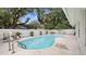 Backyard pool area featuring a white privacy fence, chaise lounges, mature palms and outdoor seating at 5417 Carlton Rd, New Port Richey, FL 34652