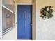 A bright blue front door to Unit 301 with a decorative wreath and a window with blinds at 5537 Sea Forest Dr # 301, New Port Richey, FL 34652