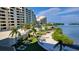 Exterior view of building with palms, pool, and a tranquil waterfront at 6035 Sea Ranch Dr # 305, Hudson, FL 34667