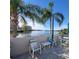 Waterfront patio with outdoor seating offers a tranquil space surrounded by palm trees and stunning water views at 6035 Sea Ranch Dr # 305, Hudson, FL 34667