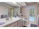 Bright bathroom featuring a white vanity, large mirror, and a door leading to the outdoor pool area at 6475 Laurel Oak Dr, Spring Hill, FL 34607