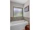 Clean white bathtub with tiled trim and a frosted window for privacy at 6475 Laurel Oak Dr, Spring Hill, FL 34607
