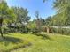 Landscaped backyard featuring a wrought iron fence that encloses the green space surrounded by mature trees and lush plants at 6821 Breezy Palm Dr, Riverview, FL 33578