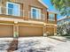 Elegant tan townhome with a multi-car garage and balcony for a scenic elevated view at 6821 Breezy Palm Dr, Riverview, FL 33578