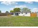 Backyard featuring a screened lanai, white exterior, partially fenced yard, and central air conditioning unit at 7034 N King Arthur E Dr # 4, Port Richey, FL 34668