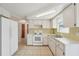Bright kitchen features white cabinets, tiled countertops and backsplash, and white appliances including an electric range at 7034 N King Arthur E Dr # 4, Port Richey, FL 34668