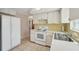 Bright kitchen features white cabinets, tiled countertops and backsplash, and white appliances including a refrigerator at 7034 N King Arthur E Dr # 4, Port Richey, FL 34668