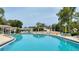 Community pool with clear blue water, lounge chairs, tables, umbrellas, and surrounding trees at 7495 Heather Walk Dr, Weeki Wachee, FL 34613