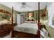 Cozy bedroom with a four-poster bed, ceiling fan, and warm green walls at 8200 Rhanbuoy Rd, Spring Hill, FL 34606