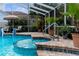 Screened pool and spa surrounded by brick trim and lounge area at 8200 Rhanbuoy Rd, Spring Hill, FL 34606