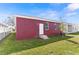 View of the home's exterior with a grassy lawn, a back door, and steps at 8312 40Th N St, Pinellas Park, FL 33781