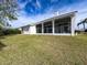 Rear exterior showing expansive lawn, screened-in patio and white exterior of the home at 8606 Coral Creek Loop, Hudson, FL 34667