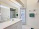 Bright bathroom with a white single sink vanity, large mirror, and a shower with glass door at 8606 Coral Creek Loop, Hudson, FL 34667
