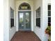 A covered front entryway showcasing double doors with decorative glass and sidelight windows at 8606 Coral Creek Loop, Hudson, FL 34667