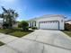 A single-story home featuring an attached two-car garage and well-maintained front lawn at 8606 Coral Creek Loop, Hudson, FL 34667