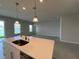 Kitchen island with stainless steel sink, quartz countertops and pendant lighting overlooking an airy living space at 10012 Zennia Ln, Parrish, FL 34219